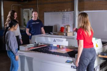 students in makerspace with laser cutter