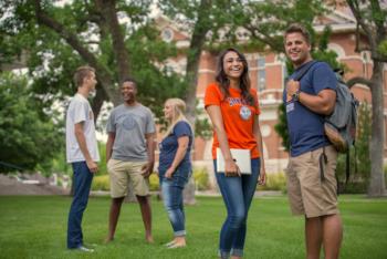 students smiling on campus lawn